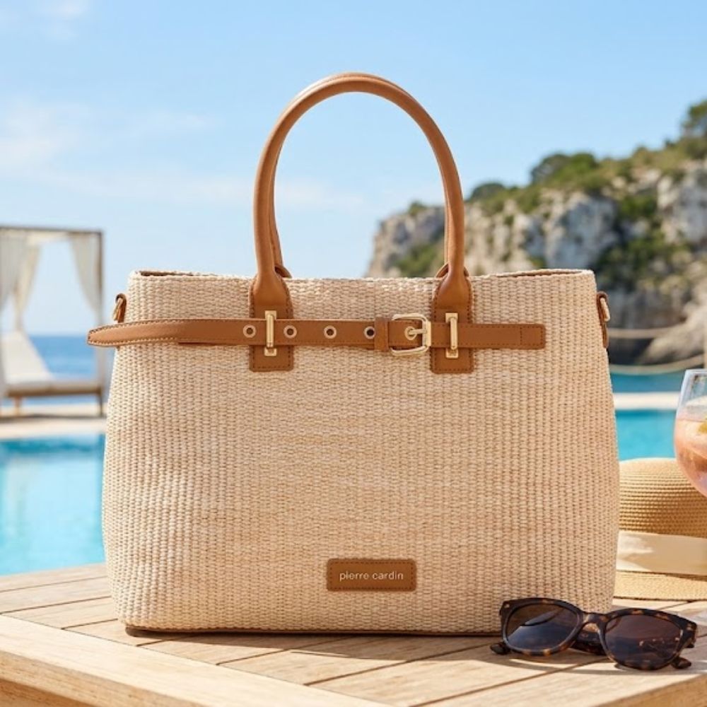 Woven handbag with brown straps on a wooden surface by a pool with a scenic background